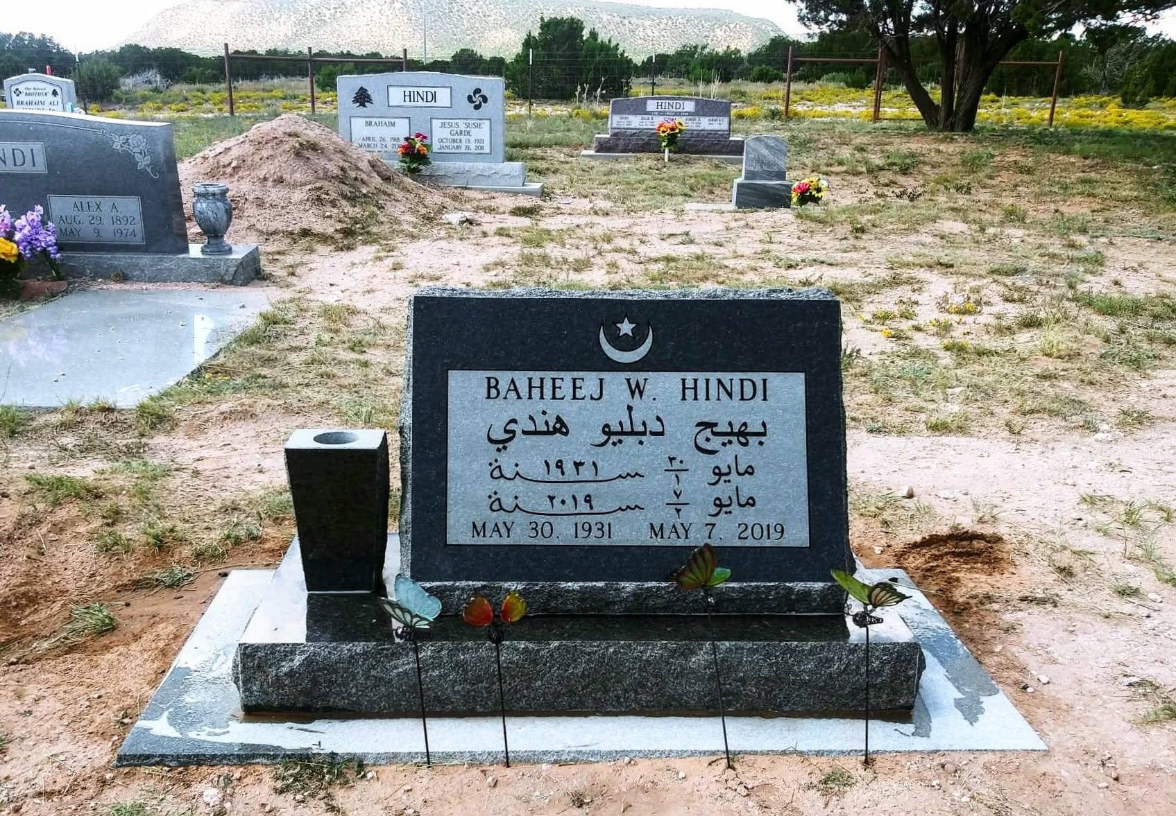 Baheej W. Hindi black granite slant monument with bilingual English and Arabic inscription, crescent and star engraving, set in a New Mexico cemetery