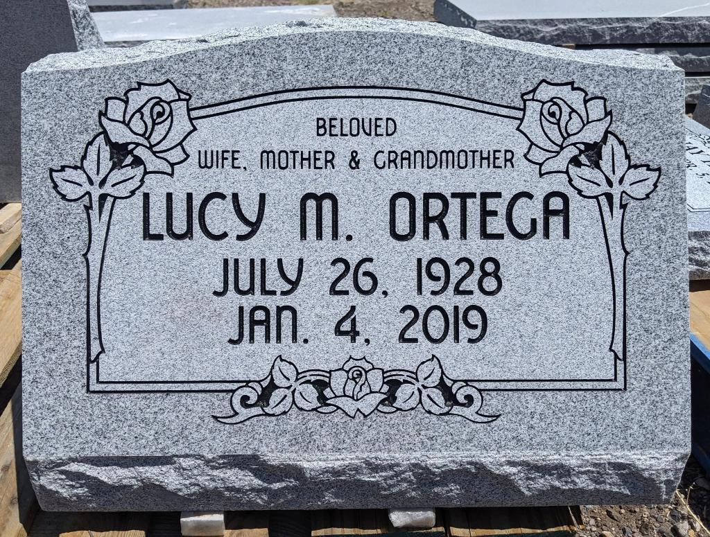 Lucy M. Ortega gray granite slant with engraved rose border frame and Beloved Wife Mother and Grandmother inscription July 26 1928 to Jan 4 2019