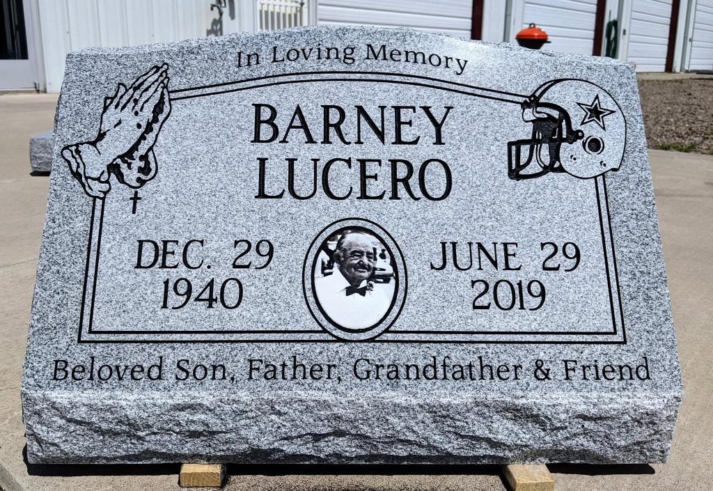 Barney Lucero gray granite slant with engraved praying hands Dallas Cowboys football helmet porcelain photo tile and Beloved Son Father Grandfather and Friend inscription Dec 29 1940 to June 29 2019