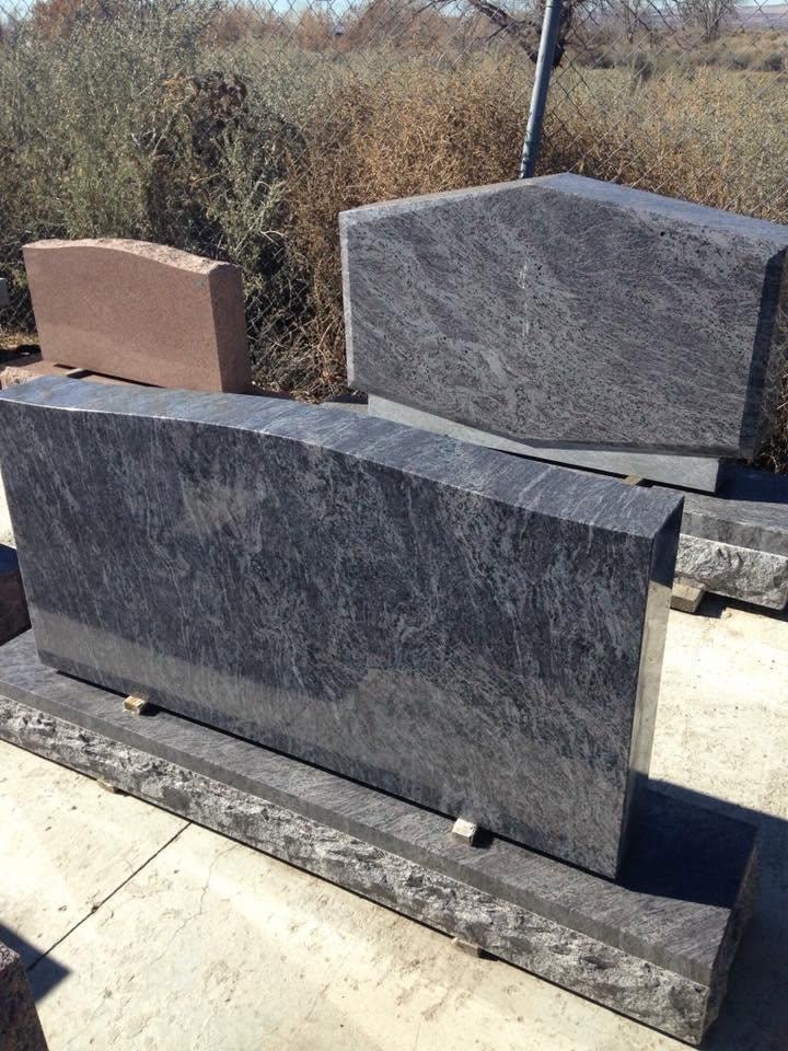 Unfinished gray granite upright monument blanks displayed outdoors on pallets in the Serenity Stone Co. yard, showing the raw stone before engraving and customization